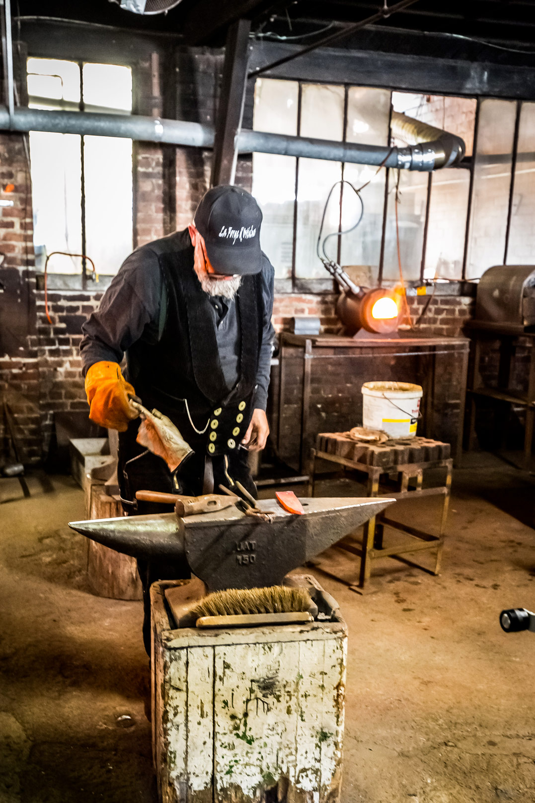 Forgeron travaillant sur l'enclume avec casquette La Forge d'Ostiches