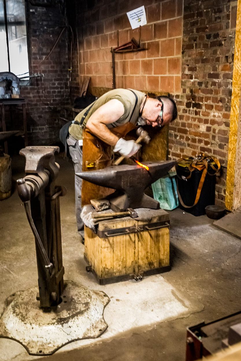 Stagiaire concentré forgeant sa lame sur l'enclume