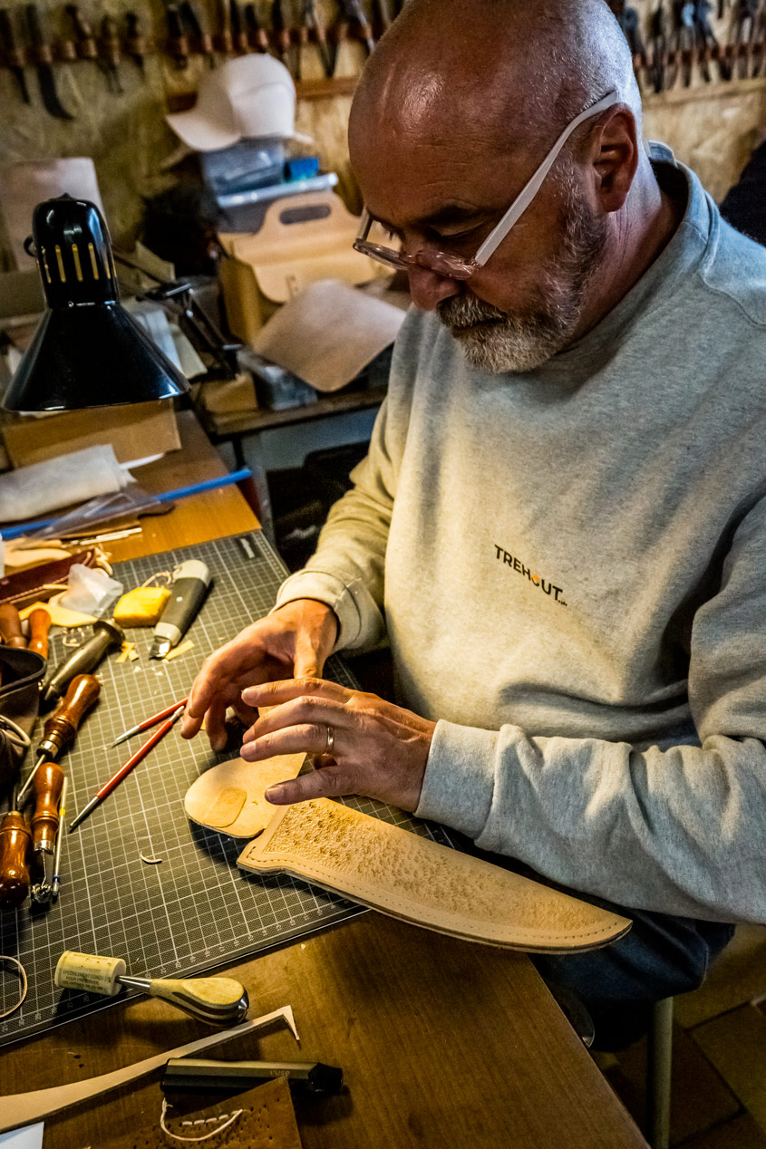 Artisan maroquinier travaillant un fourreau en cuir repoussé pour couteau forgé